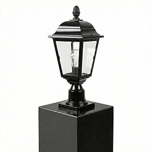 光沢のある黒い四角い柱の頂部に設置された、クラシックなデザインの黒い屋外用ポストランタン。透明なガラスパネルを通して内部の電球が見える。背景は白一色。