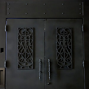 重厚感のあるブラックのオーダーメイド・ロートアイアン門扉。上部の鉄板部分に等間隔で配置された装飾リベットが、クラシックで堅牢なデザイン性を強調。